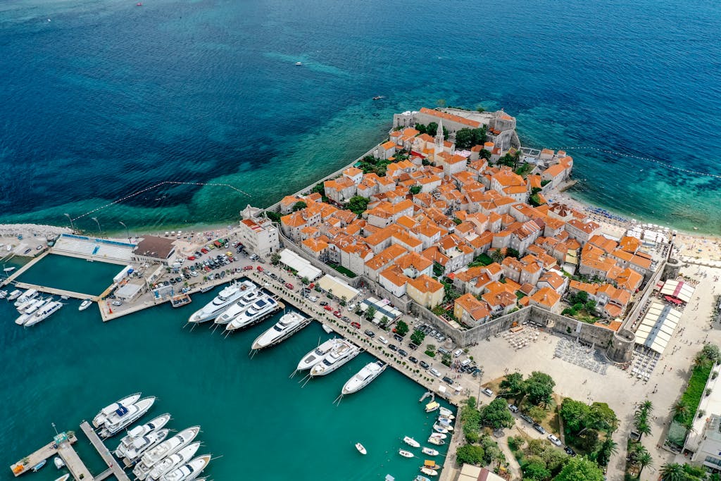A stunning aerial shot of a European old town by the coast with a marina filled with yachts.