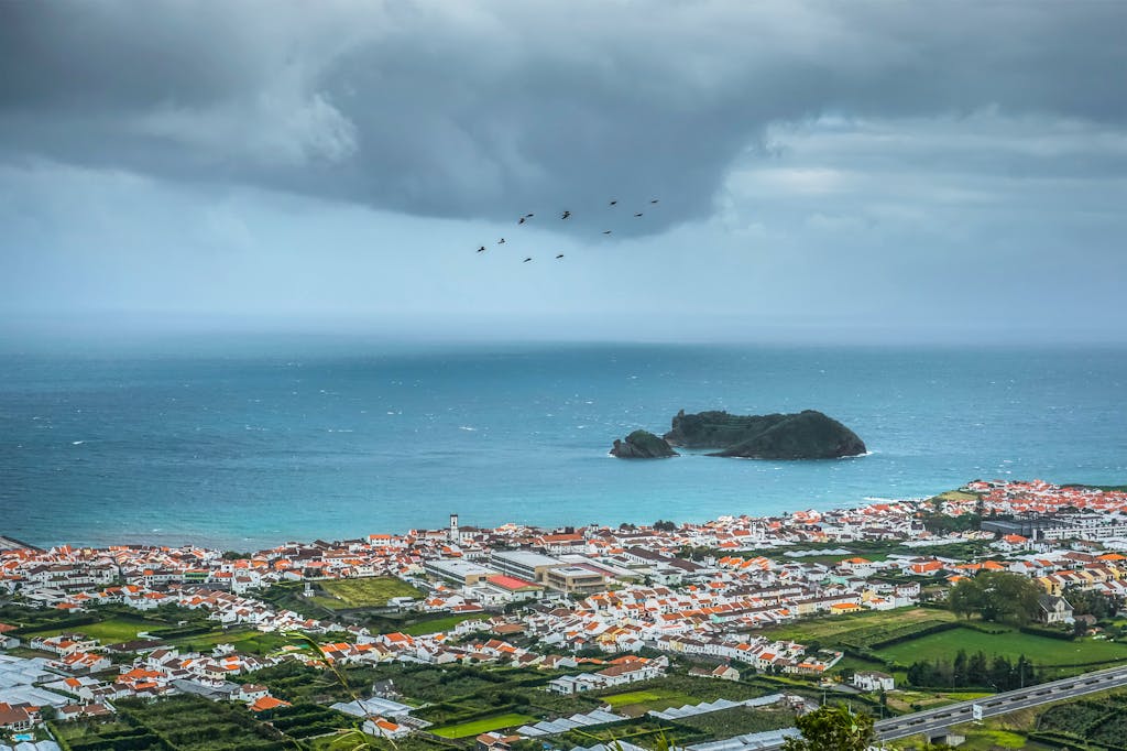 A stunning aerial view over Vila Franca do Campo and the Atlantic Ocean with dramatic clouds.