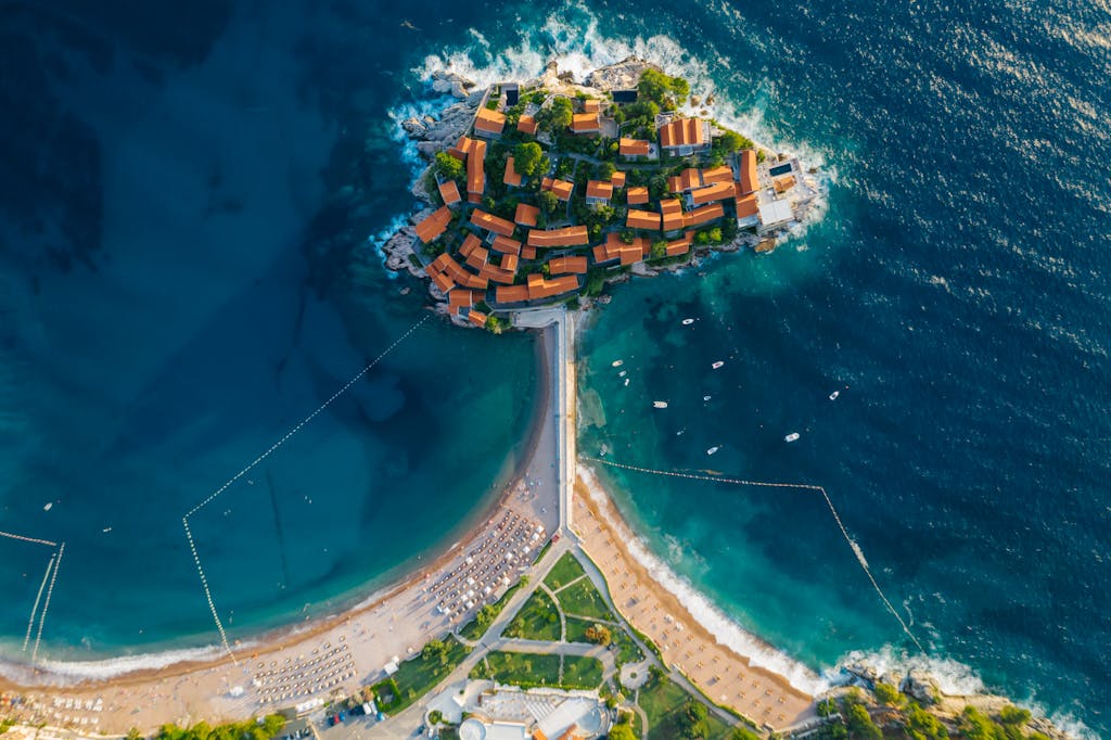 Stunning aerial photo of a coastal island with turquoise waters and vibrant roofed buildings.