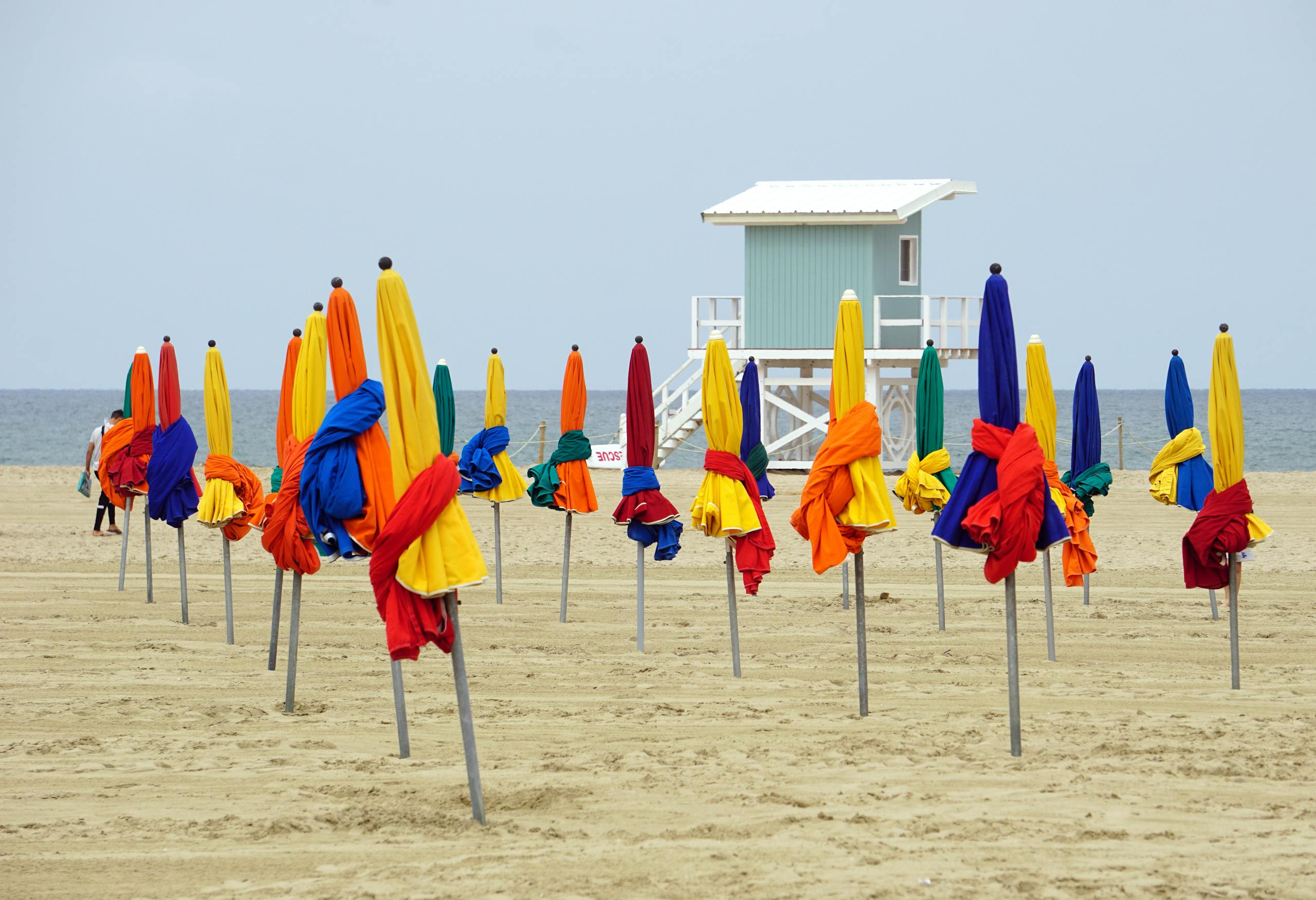 Vibrant beach umbrellas at Deauville beach in Normandie, France, with a tranquil seascape.